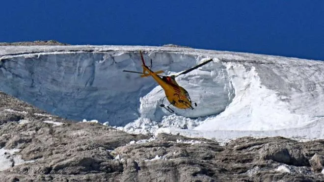 A rescue helicopter flies over the Punta Rocca glacier that collapsed near Canazei, on the mountain of Marmolada, after a record-high temperature of 10 degrees Celsius (50 degrees Fahrenheit) was recorded at the glacier's summit, on July 6, 2022. - The deadly collapse of an Italian glacier, causing an avalanche which killed at least seven people, is linked to climate change, Italy's Prime Minister Mario Draghi said on July 5, 2022. (Photo by Tiziana FABI / AFP)