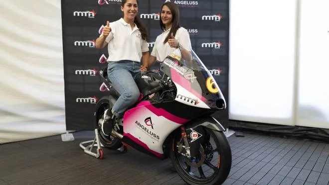 Maria Herrera in sella alla moto del team MTA in vista del Gp di Aragon; alla sua destra Aurora Angelucci di Angeluss