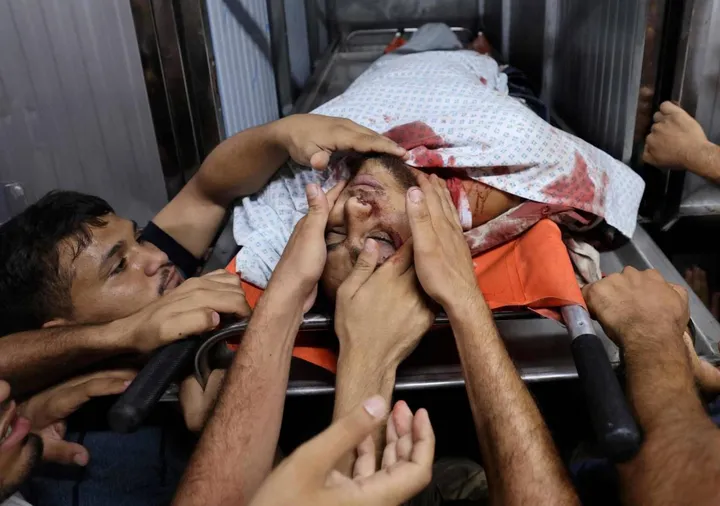 I palestinesi in lutto toccano il corpo di uno dei miliziani uccisi nel corso di un attacco aereo israeliano
