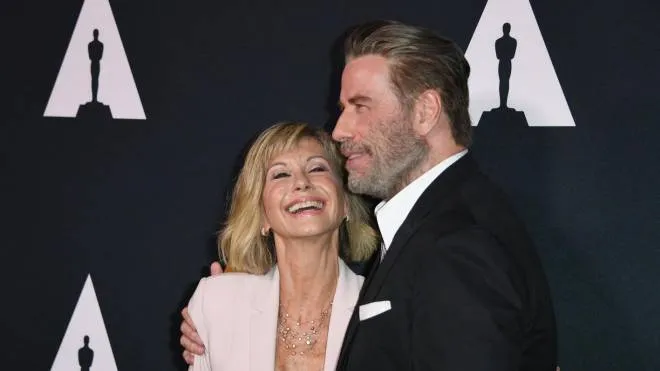 (FILES) In this file photo taken on August 15, 2018 actors Olivia Newton-John and John Travolta pose on the red carpet as they arrive for the 40th anniversary celebration of the movie "Grease" at the Academy of Motion Picture Arts and Sciences (AMPAS) in Beverly Hills, California. - Australian singer Olivia Newton-John, who gained worldwide fame as high-school sweetheart Sandy in the hit musical movie "Grease," died on August 8, 2022, her family said. She was 73. The entertainer, whose career spanned more than five decades, devoted much of her time and celebrity to charities after being diagnosed with breast cancer in 1992. (Photo by Mark RALSTON / AFP)