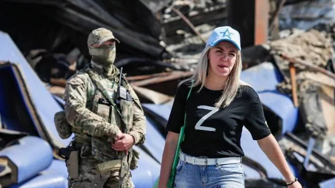 epa10147929 A picture taken during a visit to Donetsk organised by the Russian military shows Russian serviceman and a woman wearing a T-shirt with symbol Z near shopping center Galaxy damaged after shelling in Donetsk, Ukraine, 30 August 2022. On 24 February 2022 Russian troops entered the Ukrainian territory in what the Russian president declared a 'Special Military Operation', starting an armed conflict that has provoked destruction and a humanitarian crisis.  EPA/YURI KOCHETKOV