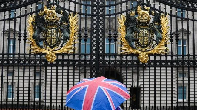 A person with an umbrella picturing the British national flag stands guard in front of Buckingham palace, central London, on September 8, 2022. - Fears grew on September 8, 2022 for Queen Elizabeth II after Buckingham Palace said her doctors were "concerned" for her health and recommended that she remain under medical supervision. The 96-year-old head of state -- Britain's longest-serving monarch -- has been dogged by health problems since last October that have left her with difficulties walking and standing. (Photo by Daniel LEAL / AFP)