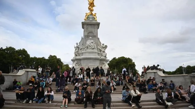 epa10170053 People sit on the steps of the Queen Victoria Memorial in front of Buckingham Palace in London, Britain, 08 September 2022. According to a Buckingham Palace statement on 08 September 2022, Britain's Queen Elizabeth II is under medical supervision at Balmoral Castle, upon the advice of her doctors concerned for the health of the 96-year-old monarch.  EPA/NEIL HALL