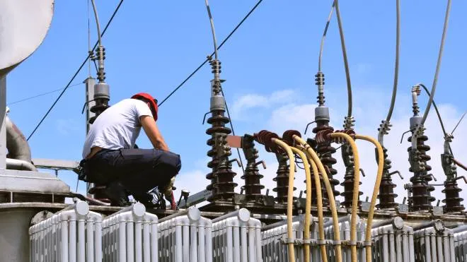 Manual worker in protective workwear and hard hat repairing electricity equipment in power plant