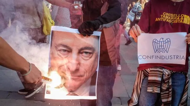 I giovani in piazza a Milano bruciano le foto di Draghi e Meloni