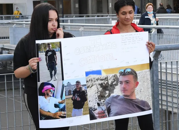 Due amiche di Giuseppe Checchia, 19 anni, reggono il cartellone con le foto del ragazzo