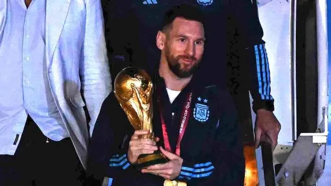 Argentina's captain and forward Lionel Messi (C) holds the FIFA World Cup Trophy as he steps off a plane upon arrival at Ezeiza International Airport after winning the Qatar 2022 World Cup tournament in Ezeiza, Buenos Aires province, Argentina on December 20, 2022. (Photo by Luis ROBAYO / AFP)