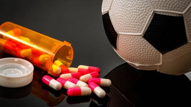 Doping in sports and steroid abuse concept with a soccer ball, a bottle of prescription pills on a dark background