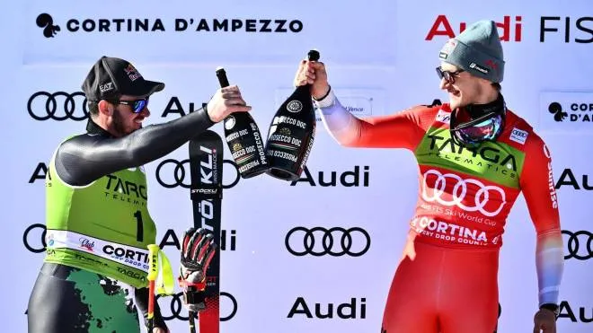 First-placed Swiss Marco Odermatt (R) and second-placed Italian Dominik Paris celebrate on the podium after the men's Super-G of the FIS Alpine Ski World Cup in Cortina d'Ampezzo on January 29, 2023. (Photo by Marco BERTORELLO / AFP)