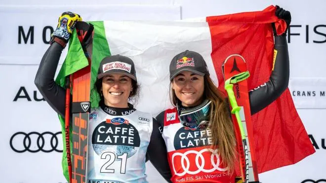 Second placed Italy's Federica Brignone (L) and winner Italy's Sofia Goggia pose with an Italian national flag during the podium ceremony of the Women's downhill event of the FIS Alpine Skiing World Cup in Crans-Montana, Switzerland, on February 26, 2023. (Photo by Fabrice COFFRINI / AFP)