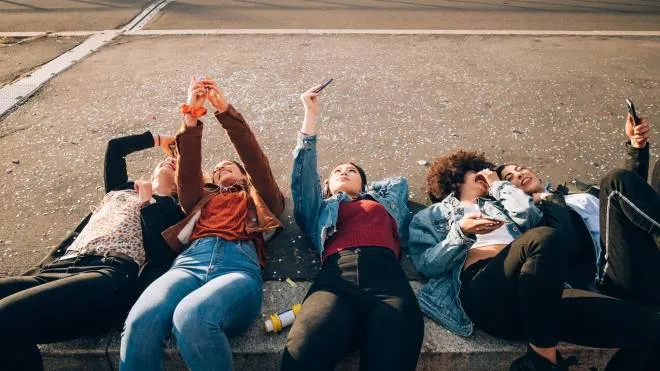 Friends together on kerb taking selfie and using smartphones, Milan, Italy (Photo by Eugenio Marongiu / Cultura Creative / Cultura Creative via AFP)