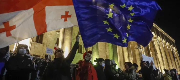 I sostenitori dei partiti dell’opposizione sventolano le bandiere georgiana ed europea davanti al Parlamento di Tblisi