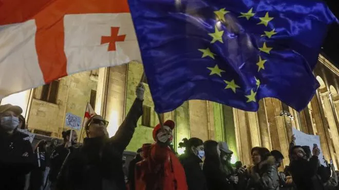 I sostenitori dei partiti dell’opposizione sventolano le bandiere georgiana ed europea davanti al Parlamento di Tblisi
