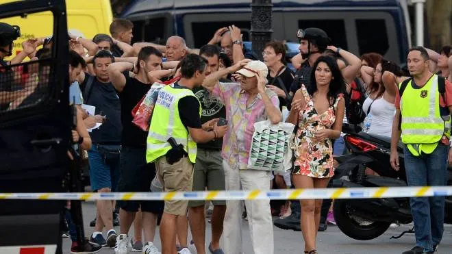 Policemen check the identity of people standing with their hands up after a van ploughed into the crowd, killing two persons and injuring several others on the Rambla in Barcelona on August 17, 2017.
A driver deliberately rammed a van into a crowd on Barcelona's most popular street on August 17, 2017 killing at least two people before fleeing to a nearby bar, police said. 
Officers in Spain's second-largest city said the ramming on Las Ramblas was a "terrorist attack" and a police source said one suspect had left the scene and was "holed up in a bar". The police source said they were hunting for a total of two suspects. / AFP PHOTO / Josep LAGO