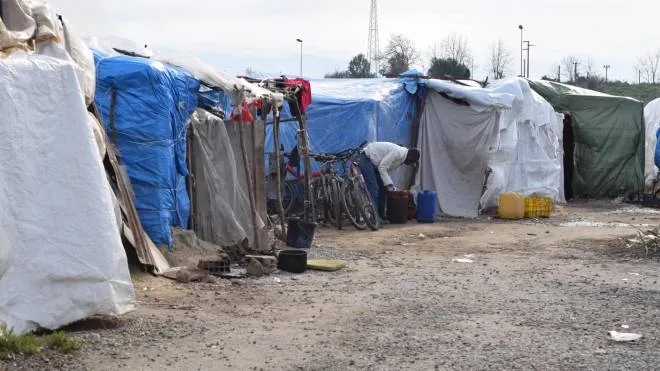 In this photo taken on Tuesday, Feb. 2, 2016, a man adjusts his belongings in the tent city of San Ferdinando, Southern Italy, where about 1,200 migrants and refugees live without access to basic services. Thousands of migrants, many from Africa, who harvest oranges in the southern Italian region of Calabria during the fruit-picking season, live on meager wages and in squalid conditions, some in abandoned farmhouses or derelict factories, often with no running water or electricity. (ANSA/AP Photo/Annalisa Camilli)