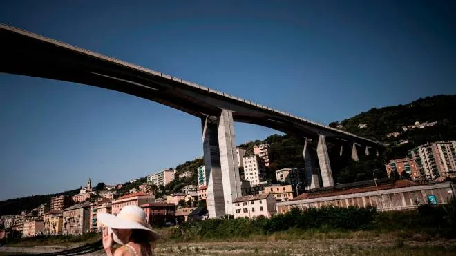 A woman walks near the E80 highway bridge of Staglieno in Genoa on August 17, 2018, which is one of the largest in Genoa. - Genoa, Italy's largest port, is a vertical city, stretching from its harbour to the slopes of the Apennine mountain range,  its various segments are linked by five road tunnels and high bridges. A section of one these bridges - The Morandi Bridge - collapsed on August 14, causing the deaths of at least 39 people. (Photo by MARCO BERTORELLO / AFP)