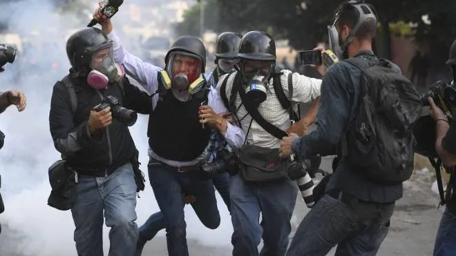 Venezuelan VPITV journalist Gregory Jaimes (C) is assisted by colleagues after being injured during clashes of anti-government protesters and security forces during the commemoration of May Day on May 1, 2019 after a day of violent clashes on the streets of the capital spurred by Venezuela's opposition leader Juan Guaido's call on the military to rise up against President Nicolas Maduro. - Guaido called for a massive May Day protest to increase the pressure on Venezuelan President Nicolas Maduro. (Photo by Federico Parra / AFP)