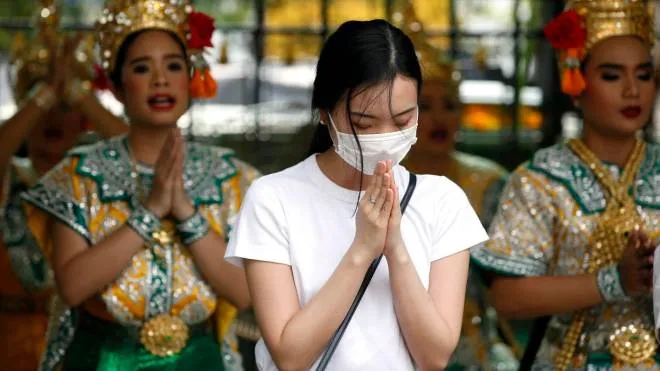 epa08144063 A worshipper wearing protective mask offers prayers with Thai dancers performing to worship Lord Brahma, the Hindu God of creation, at the Chinese tourist popular spot of Erawan Shrine in Bangkok, Thailand, 20 January 2020. Thai health official confirmed its found two case of coronavirus infected from two Chinese women tourist traveled from China's Wuhan city.  EPA/RUNGROJ YONGRIT