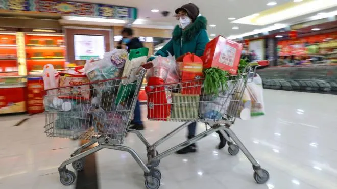 epaselect epa08163559 A masked shopper moves two trolleys out of a supermarket in Wuhan in central China's Hubei province 25 January 2020. The city struck by the 2019-nCoV virus will ban private traffic starting on Sunday, prompting citizens to a shopping spree of necessities and groceries.  EPA/YUAN ZHENG CHINA OUT