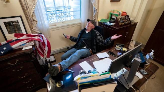 Un assalitore del Congresso si siede alla scrivania di Nancy Pelosi (Ansa)
