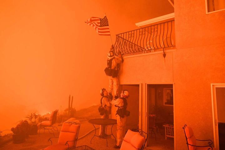Vigili del fuoco mettono in salvo la bandiera americana durante gli incendi in California, 8 luglio 2017 (Afp, Josh Edelson)