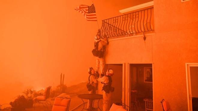 Vigili del fuoco mettono in salvo la bandiera americana durante gli incendi in California, 8 luglio 2017 (Afp, Josh Edelson)