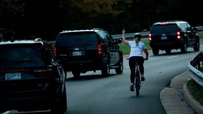 Una donna in bicicletta alza il dito medio all'arrivo dell'auto che trasporta il presidente Usa Donald Trump, 28 ottobre 2017 (Afp, Brendan Smialowski)