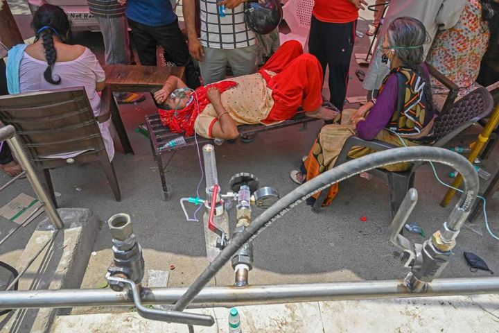 Paziente respira con l'aiuto dell'ossigeno fornito da un Gurdwara, un luogo di culto per i sikh, sotto una tenda installata lungo la strada (Ansa)