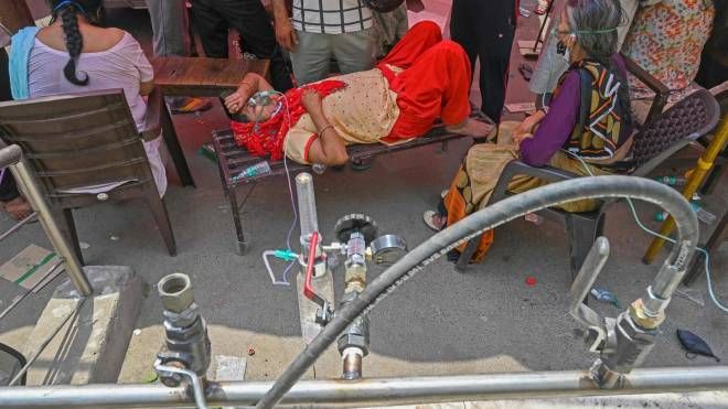 Paziente respira con l'aiuto dell'ossigeno fornito da un Gurdwara, un luogo di culto per i sikh, sotto una tenda installata lungo la strada (Ansa)