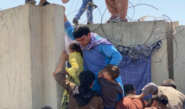 Persone scavalcano il muro dell'aeroporto per provare a fuggire (Ansa)