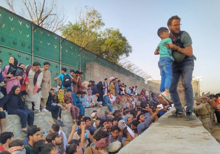 Il console italiano a Kabul Tommaso Claudi aiuta un bambino spaventato a superare il muro dell'aeroporto (Ansa)