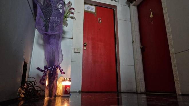 Una candela, un angioletto di ceramica e un vasetto con dei fiori di fronte alla porta rossa di Martha Castano Torres, una delle tre donne uccise giovedì a Roma, 19 novembre 2022.