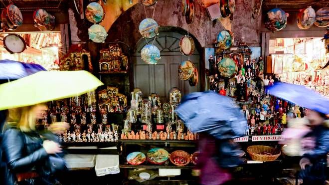 Ombrelli aperti per la pioggia insistente per i turisti in visita al mercatino del presepe nei vicoli di San Gregorio Armeno a Napoli