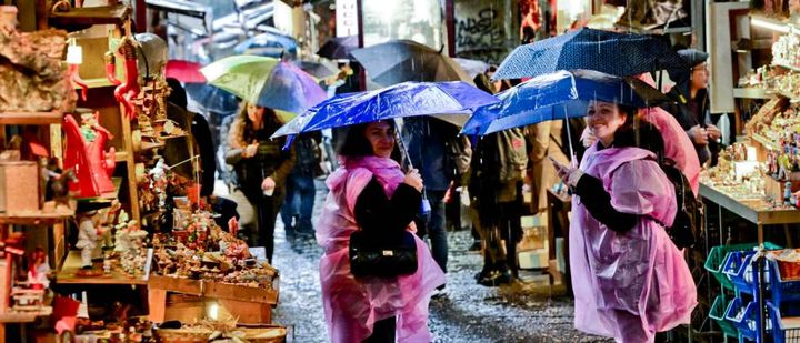 Ombrelli aperti per la pioggia insistente per i turisti in visita al mercatino del presepe nei vicoli di San Gregorio Armeno a Napoli