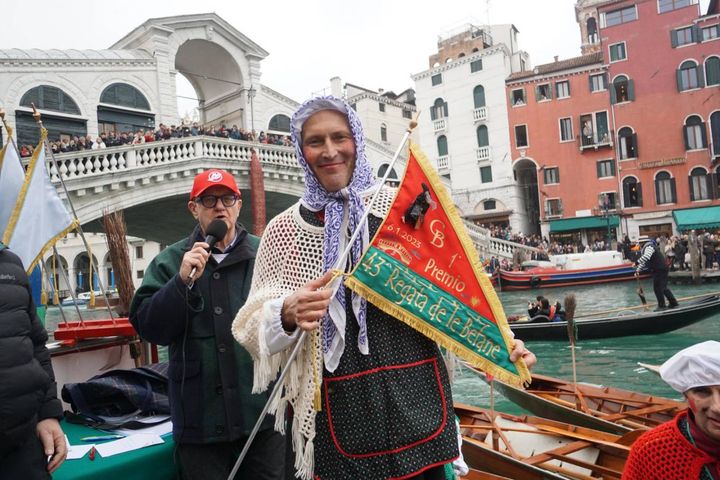 La befana Riccardo Romanelli, regatante della Reale Canottieri Bucintoro, posacon la bandiera da vincitore sotto il ponte di Rialto, sul Canal Grande, alla 43°esima edizione della Regata delle Befane, oggi 6 gennaio 2023.