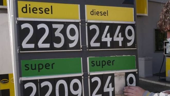 Un benzinaio mentre aggiorna i prezzi dei carburanti