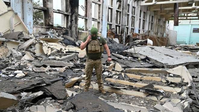 Un militare ucraino tra le macerie di un edificio dell'Università di Kharkiv (Ansa)
