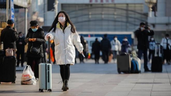 Passeggeri con mascherina di fronte alla stazione dei treni di Pechino